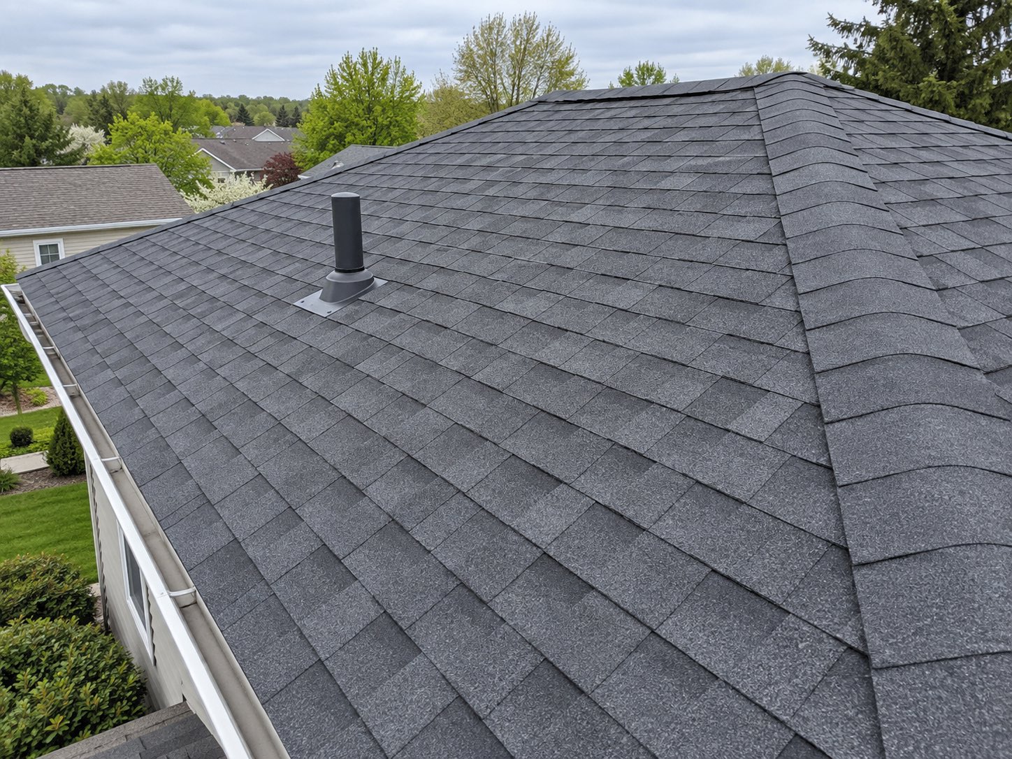 A finished asphalt shingle roof with new courses, a new ridge cap and a new vent boot